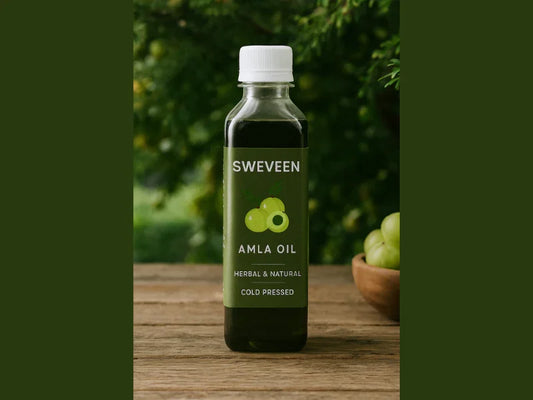 Amla oil in a bottle, on a wooden surface, with amla fruits in the background.