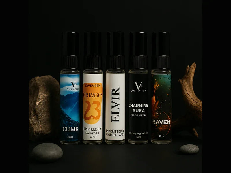 Five small perfume bottles with black caps, arranged between rocks and a piece of wood on a black surface.
