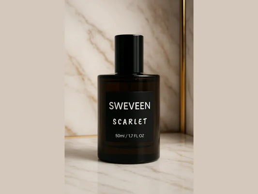 Dark glass perfume bottle with black label on a marble surface.